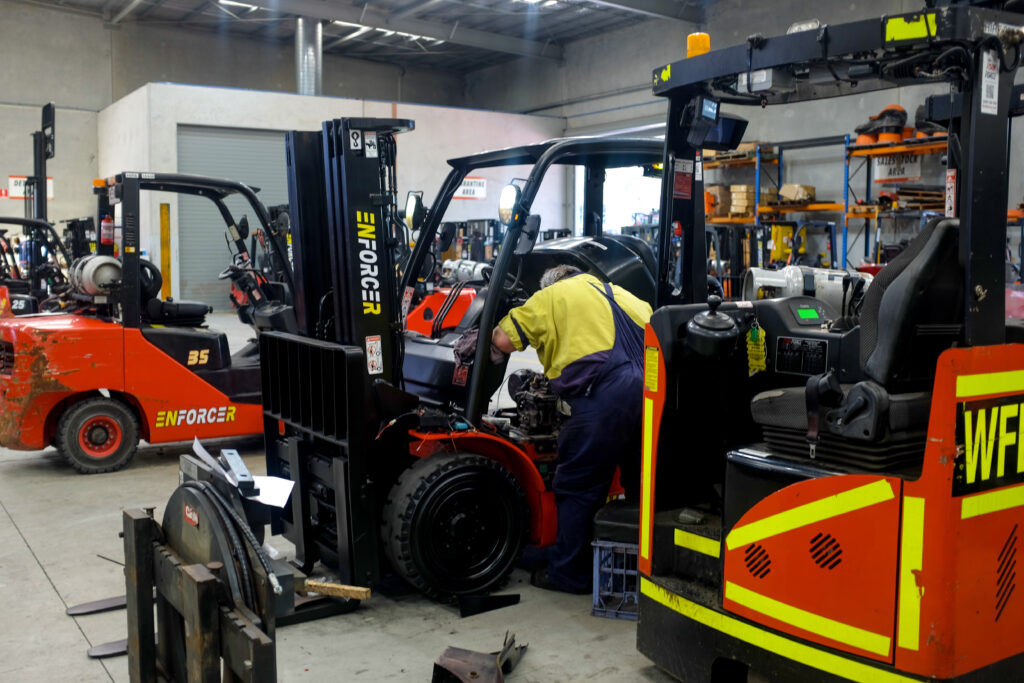 Forklift service technician working on an Enforcer forklift in a workshop