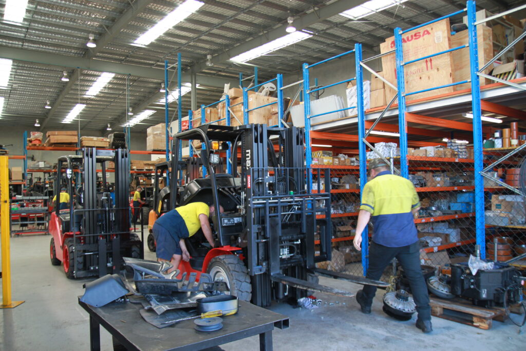 Fork Force Forklift Service Technician Inspecting Forklift Fork Force Forklift Service Technician Inspecting Forklift in Workshop